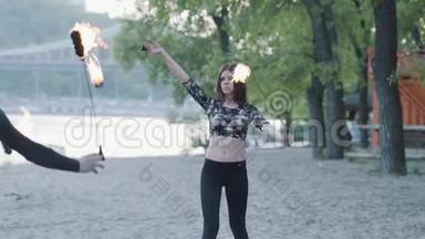 戴着面具的年轻可爱女人在树前用火焰表演节目的肖像。 熟练的火技艺术家展示